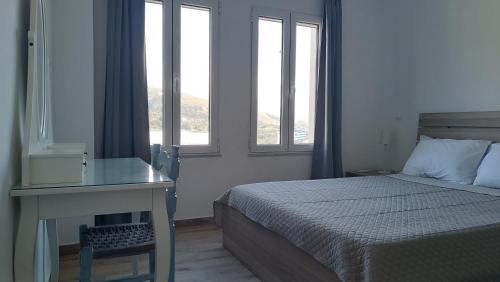 1 dormitorio con 1 cama y escritorio con ventanas en Azalea Guesthouse, en Ándros