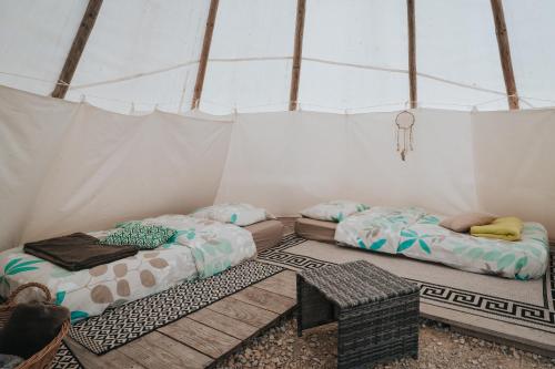 dwa łóżka w namiocie ze stołem w obiekcie Tipi / Nature / Détente w mieście Bragny-sur-Saône