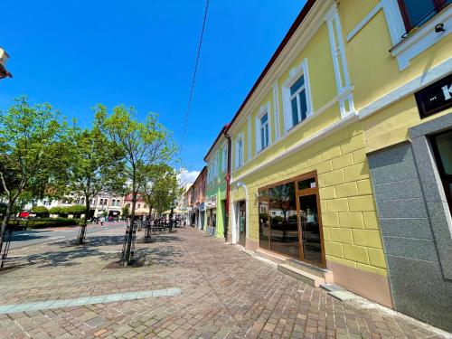 a cobblestone street in front of a yellow building at Royal Apartments Liptovsky Mikulas in Liptovský Mikuláš