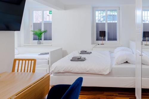 a white bedroom with two beds and a table at Apartments am Hauptbahnhof in Rostock
