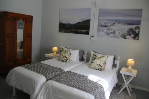 a bedroom with a bed with white sheets and pillows at @karoo Guesthouse in Graaff-Reinet