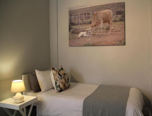 a bedroom with a bed and a cow laying on the ground at @karoo Guesthouse in Graaff-Reinet