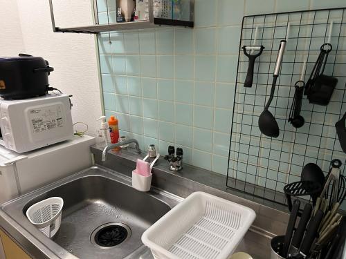 a kitchen with a sink and a microwave at Guest House Nishijin INN in Fukuoka