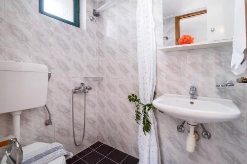 ein weißes Bad mit einem Waschbecken und einer Dusche in der Unterkunft Nikoleta Studio 5 in Nikiana