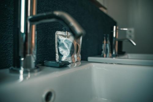 - un lavabo avec un robinet et une bouteille dans l'établissement Le sérénité - T3 en maison de ville avec piscine, à Annecy