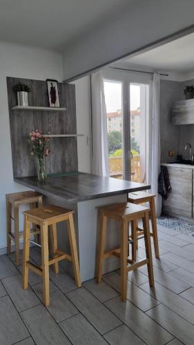 une cuisine avec une table et deux tabourets ainsi qu'une fenêtre dans l'établissement Martigues centre, à Martigues