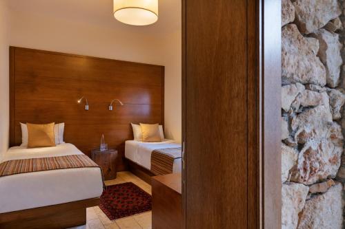 a hotel room with two beds and a stone wall at Beresheet by Isrotel Exclusive in Mitzpe Ramon