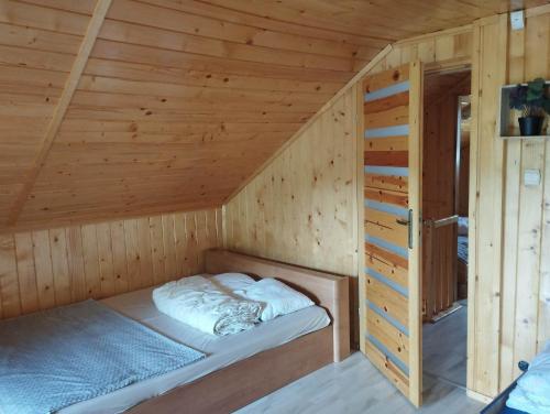 a bed in a cabin with a wooden ceiling at Osada nad żurawim stawem in Krzywogonice