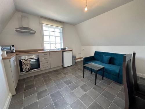 a living room with a blue couch and a kitchen at 1 Bed Central Newark Flat 2nd Floor in Newark upon Trent