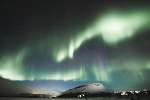 an aurora in the sky over a mountain at Lapland Hotels Kilpis in Kilpisjärvi