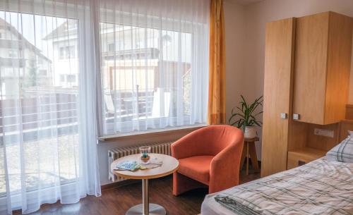 ハーグナウにあるHaus Schwörerのベッド1台、椅子、窓が備わる客室です。