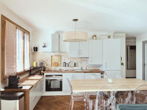 une cuisine avec des armoires blanches et une table et des chaises dans l'établissement Les Clairières - spacieux T3 tout à pied, à Annecy