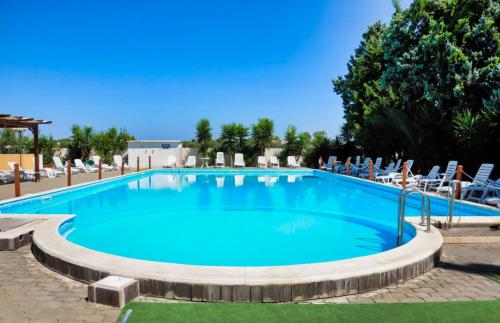 a large swimming pool with chairs around it at Hotel Villaggio Aurora in San Pietro in Bevagna