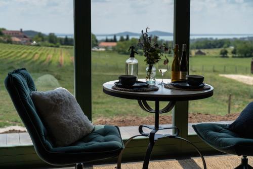 a table with two chairs and a table with wine bottles at Istvándy Birtok in Káptalantóti