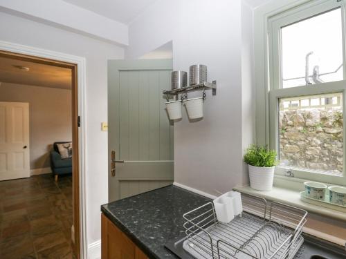 a kitchen with a dish drying rack and a window at Meadowbank Cottage in Carnforth