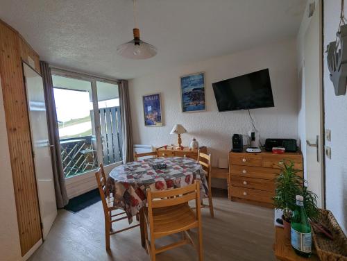 une salle à manger avec une table, des chaises et une télévision dans l'établissement Combe Blanche 1217, à Manigod