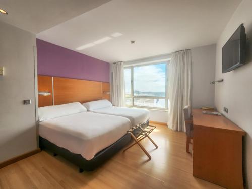 1 dormitorio con cama, escritorio y ventana en Hotel Faranda Marsol Candás, en Candás