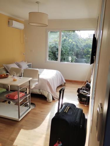 Un dormitorio con una cama y una mesa con una maleta en Mel en Tandil