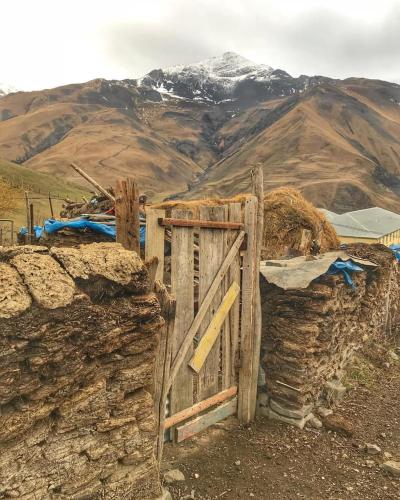 a wooden gate on a stone wall with a mountain at Xinaliq Khinalig İzzet's Riverside Home Stay in Xınalıq