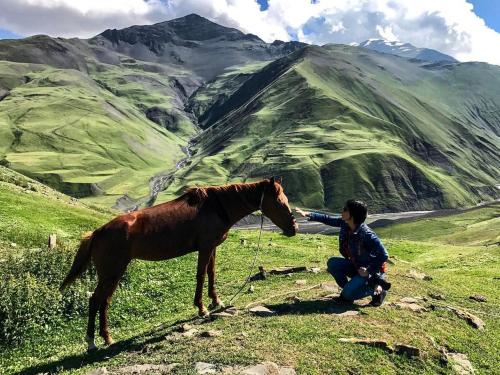 a man is petting a horse on a mountain at Xinaliq Khinalig İzzet's Riverside Home Stay in Xınalıq