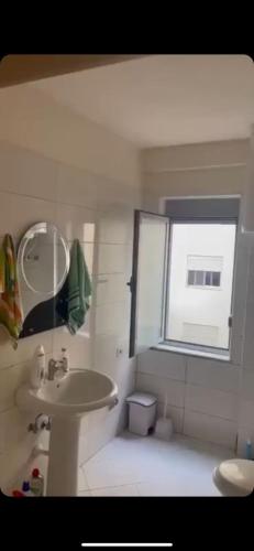 uma casa de banho com um lavatório, um espelho e uma janela em Sunset Apartment em Durrës