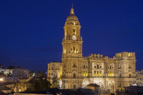a building with a clock tower at night at Petit Palace Plaza Málaga in Málaga