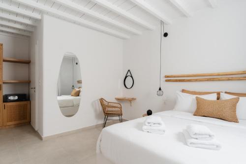 a white bedroom with a large white bed and a chair at Penelope Village in Kalo Livadi