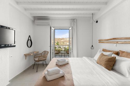 a white bedroom with a bed and a balcony at Penelope Village in Kalo Livadi