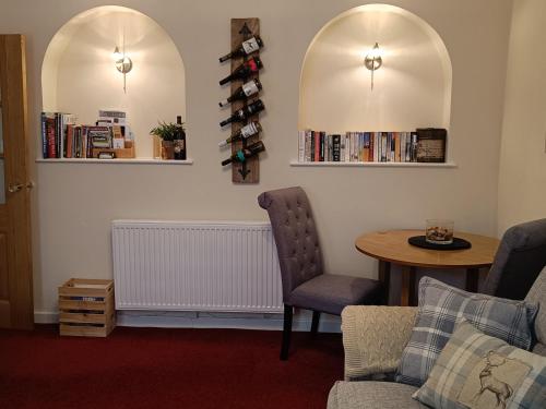 a living room with a table and a chair at Cosy cottage in the heart of Pateley Bridge. in Pateley Bridge