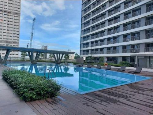 a large swimming pool with chairs and a building at Mari Dul's Place @ Fame Residence in Manila