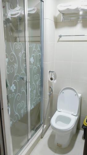 a bathroom with a toilet and a glass shower at Mari Dul's Place @ Fame Residence in Manila