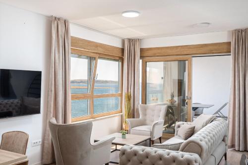 a living room with a couch and chairs and windows at Salt&Soul Residence in Povljana