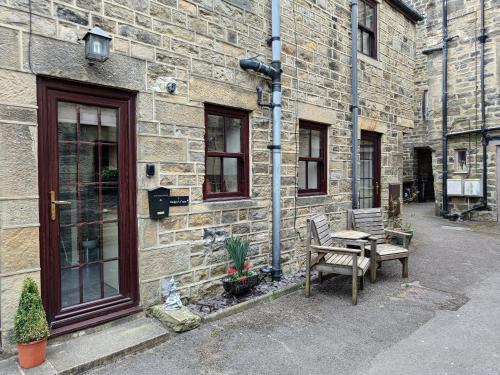 a bench and a table outside of a brick building at Cosy cottage in the heart of Pateley Bridge. in Pateley Bridge