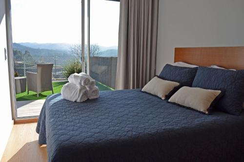 Schlafzimmer mit einem blauen Bett und einem großen Fenster in der Unterkunft Campo Seco in Vieira do Minho