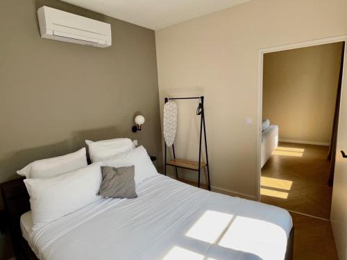 a bedroom with a bed with white sheets and a fan at Legend - Parking privé - Gare - Centre ville - Quai de Saône - fibre in Mâcon