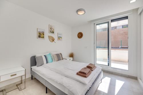 a white bedroom with a bed and a window at Penthouse with private pool in La Cala de Mijas
