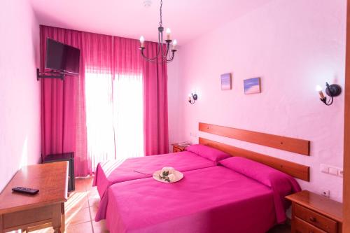 a bedroom with a pink bed with a hat on it at Hotel Oasis Atalaya in Conil de la Frontera