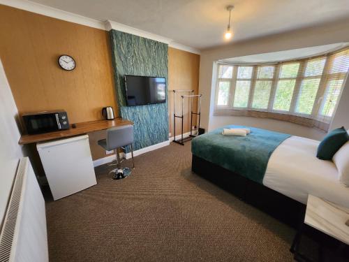 a hotel room with a bed and a desk and a tv at Solihull Shared House in Birmingham