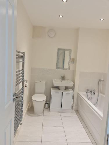 a white bathroom with a toilet and a sink at Mills Home Stays in Derby