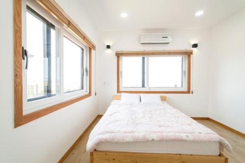 a small bedroom with a bed and a window at Onthestone Pension in Seogwipo