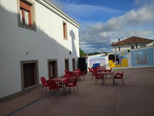 grupa stołów i krzeseł obok budynku w obiekcie Albergue Miraiso w mieście Arzúa