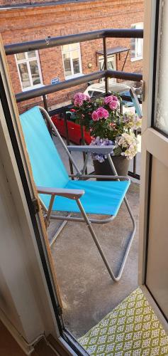 a blue chair on a balcony with a table and flowers at Centrum lägenhet in Skövde