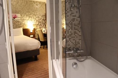 パリにあるティモテル オデッサ モンパルナスのバスルーム(バスタブ付)、ベッドルーム(ベッド付)が備わります。