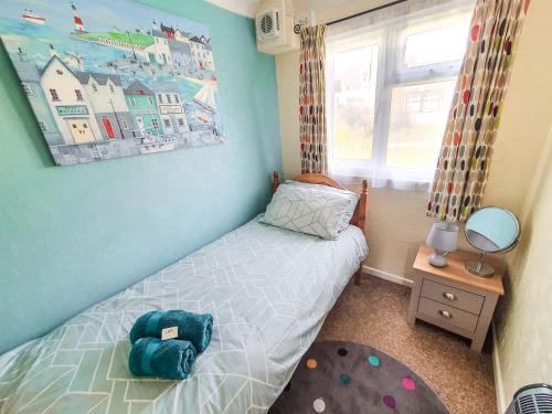a small bedroom with a bed and a window at Dart Haven - cheerful holiday bungalow in Galmpton in Galmpton-on-the-Dart