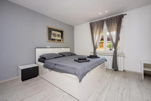 a white bedroom with a large bed and a window at Apartments Luna in Dramalj