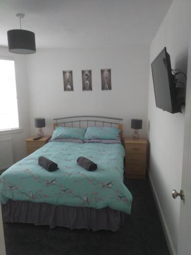 a bedroom with a bed with two pillows on it at J & S Apartments in Ayr
