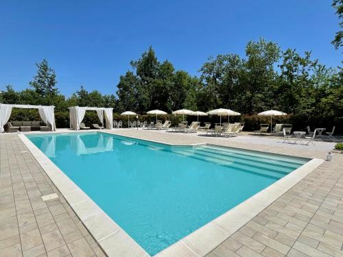 a large swimming pool with chairs and umbrellas at La quercia B&B in Abbateggio