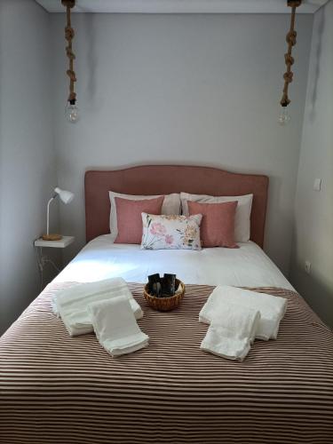 a cat sitting in a basket on a bed with two towels at Casa da Padaria in Folgosa