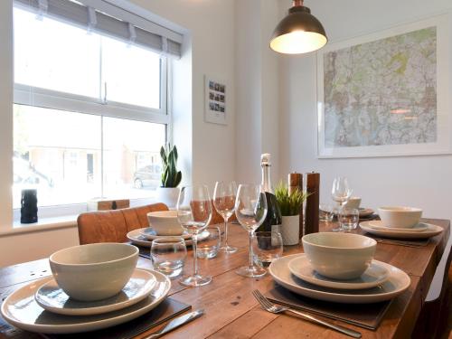 a wooden table with plates and wine glasses on it at Pass the Keys Beautiful Family Home Sleeps 6 in Emsworth