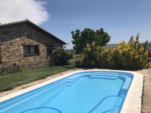 a pool in front of a stone house at Ruta Del Aguila alojamiento turístico de calidad in Santa María de la Alameda